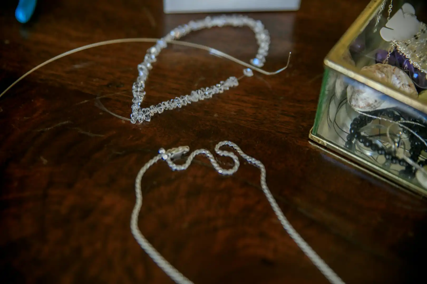 Broken silver chain and crystal necklace on a wooden table, ready for professional jewelry repair in Milton.